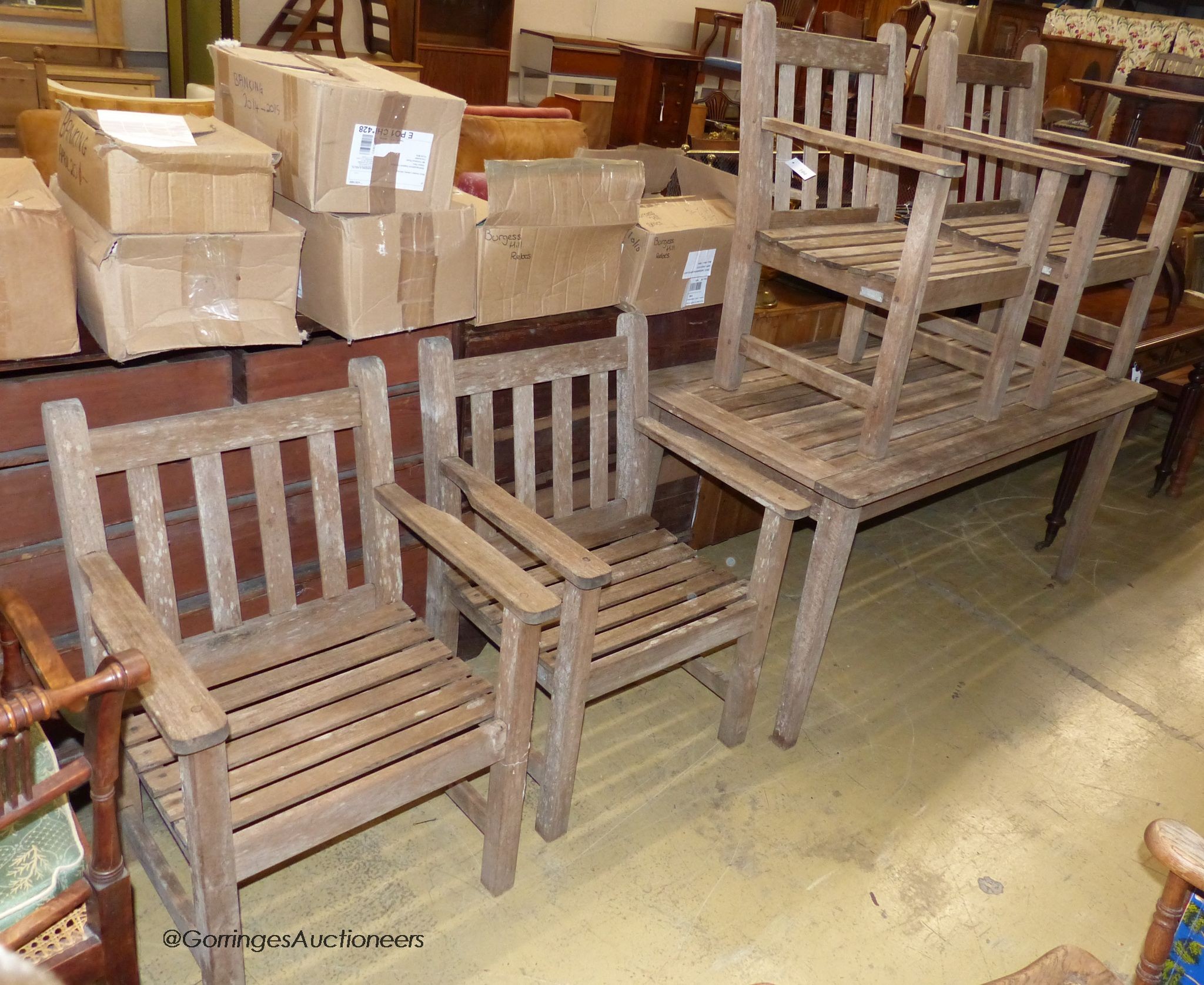 A rectangular weathered teak garden table, length 150cm, depth 71cm, height 68cm together with four weathered teak garden elbow chairs, labelled Barlow Tyrie Ltd.